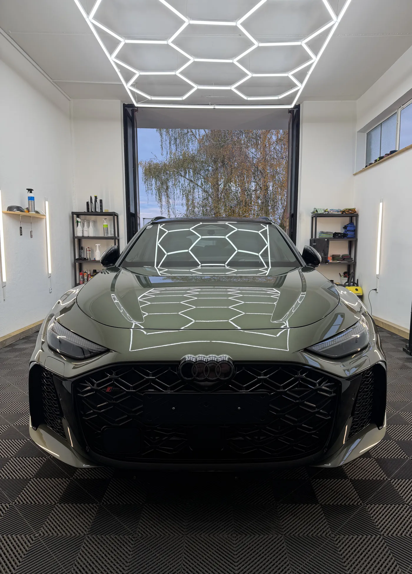 Grüner Audi RS5 Avant frontal in der Halle von MB Autopflege, die Wabenleuchte spiegelt sich in Haube und Scheibe